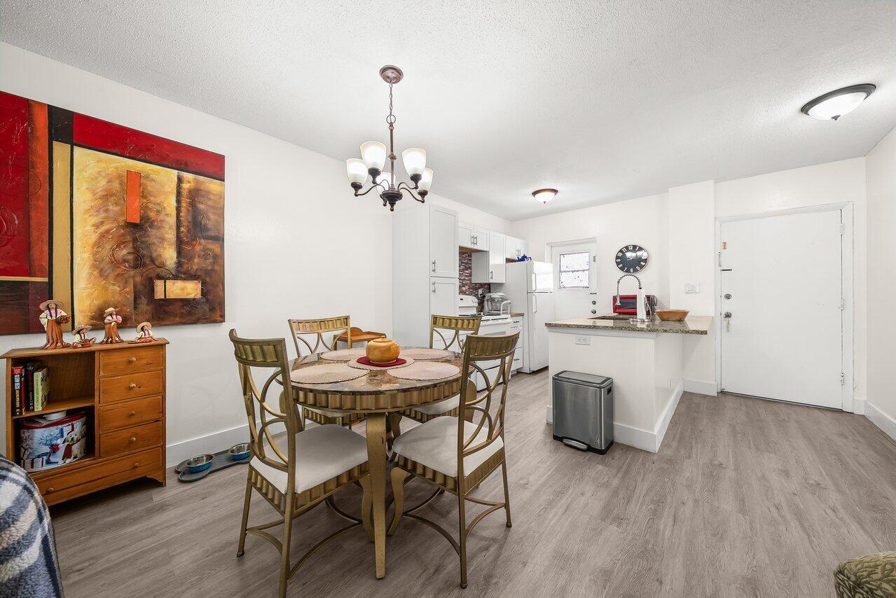 A dining area with a round table and chairs sits adjacent to an open kitchen — 1117 Lake Terrace # 207, Boynton Beach FL 33426, BOYNTON BEACH, FL