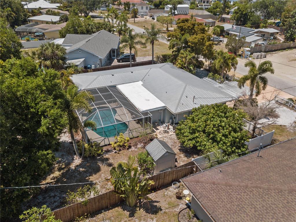 An aerial view shows a house with a metal roof, screened pool, and backyard shed — 7860 HOLIDAY DRIVE, SARASOTA, FL