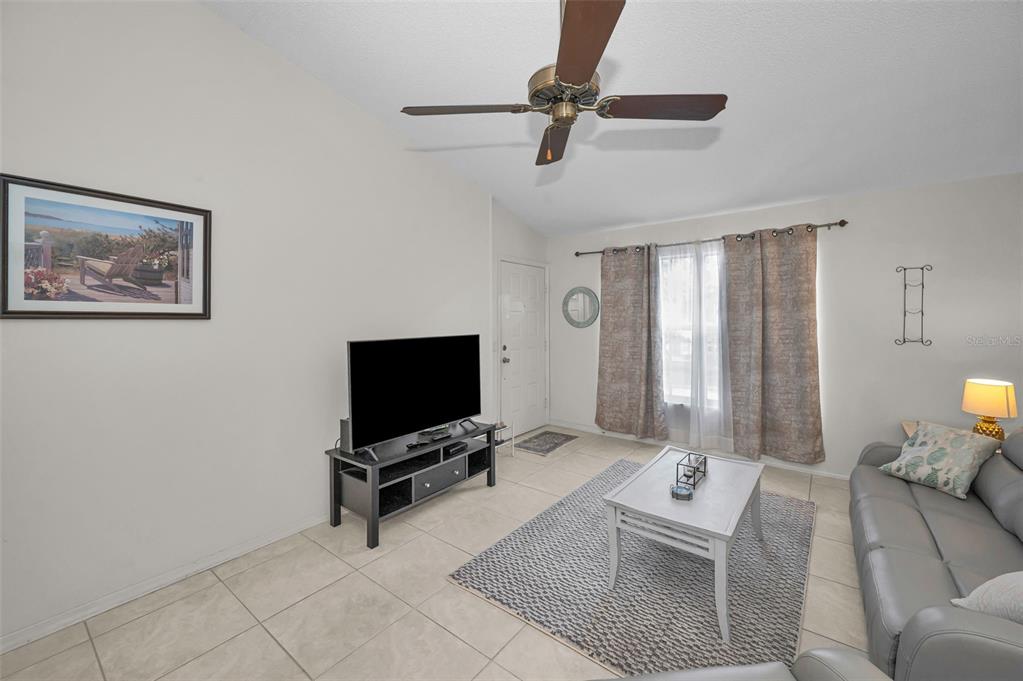 A living room features tile flooring, a ceiling fan, a television on a stand, and a sofa — 7837 HARDWICK DRIVE UNIT 327, NEW PORT RICHEY, FL