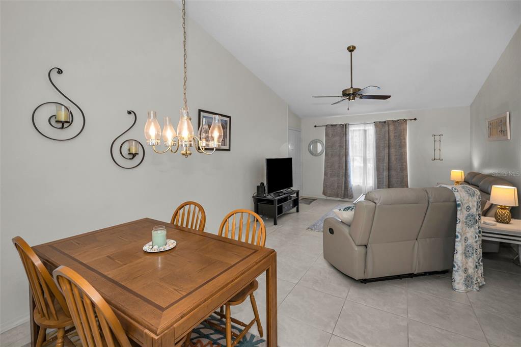 A dining area with a wooden table and chairs opens into a living room — 7837 HARDWICK DRIVE UNIT 327, NEW PORT RICHEY, FL