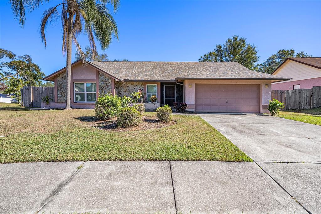 A single-story house with a stone facade, a two-car garage, and a palm tree — 1606 DUSTY ROSE LANE, BRANDON, FL