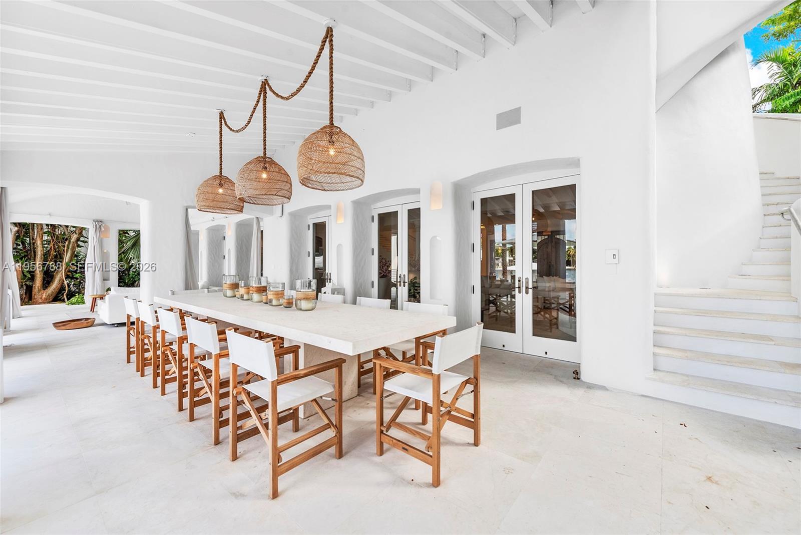 A long outdoor dining table with wooden chairs sits under a white covered patio — 24 S Hibiscus Dr, Miami Beach FL 33139, MIAMI BEACH, FL