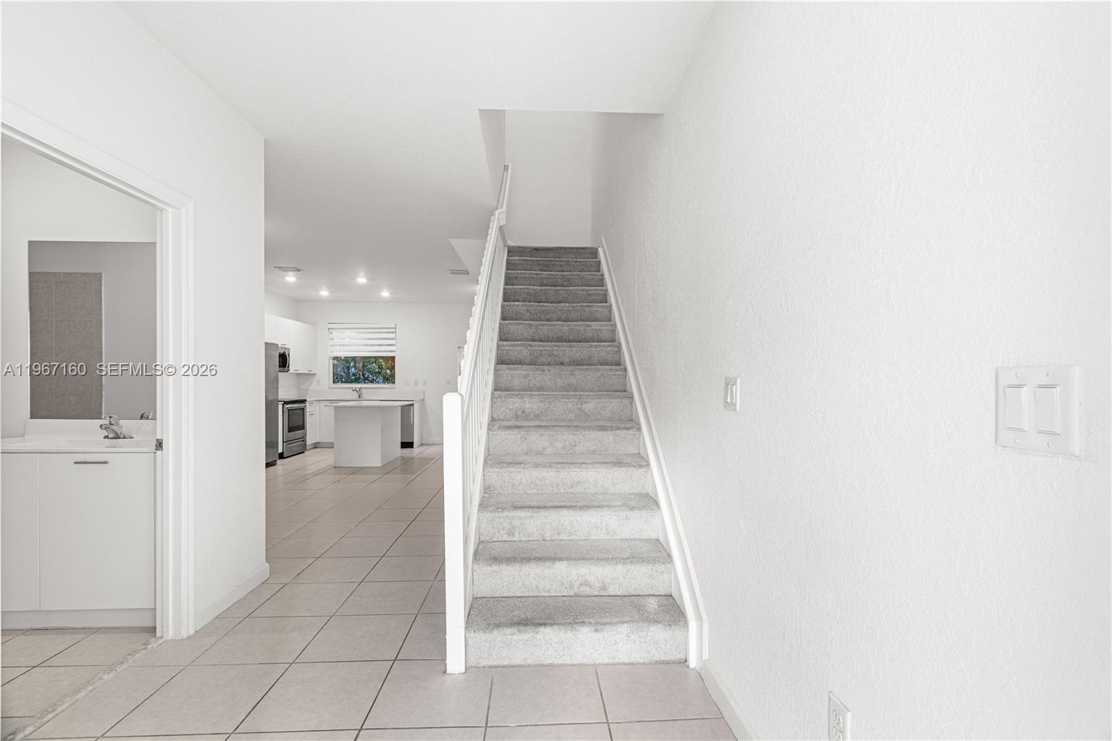 A modern kitchen features white cabinets, stainless steel appliances, a center island, and sliding doors — 12121 NW 23rd Ct, Miami FL 33167, MIAMI, FL