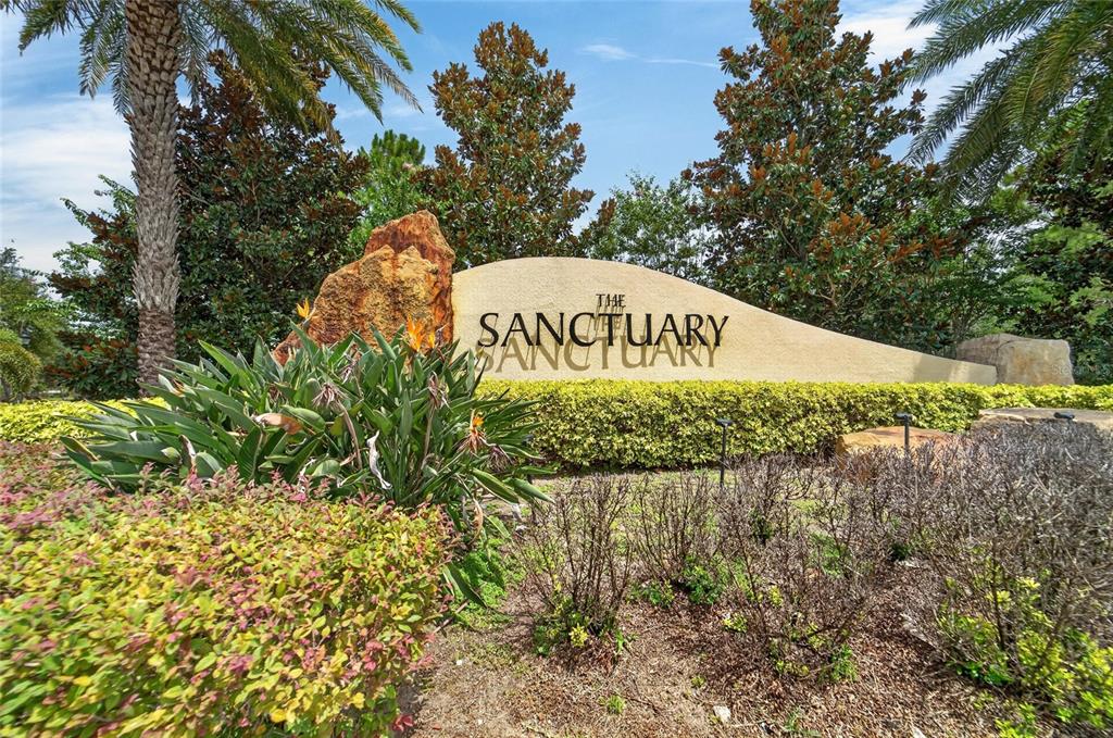 A stone monument sign for The Sanctuary stands amidst landscaping, palm trees, and shrubs — 12111 FAWN BRINDLE STREET, RIVERVIEW, FL