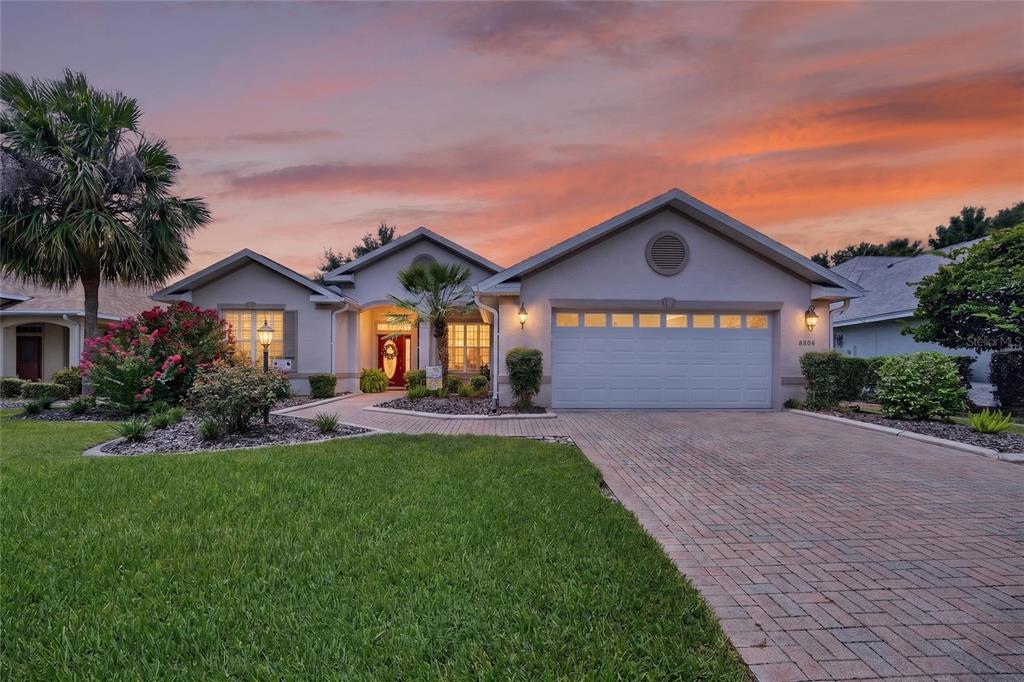 A single-story house with a brick driveway, a two-car garage, and a sunset sky — 8806 SW 83RD CIRCLE, OCALA, FL