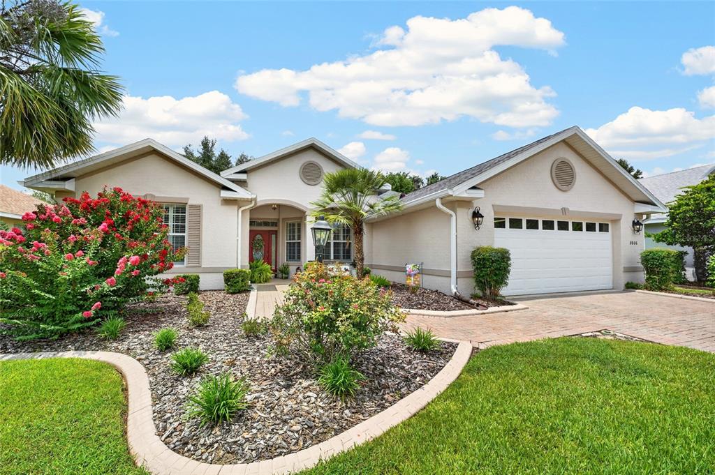 A single-story house with a beige stucco exterior, a two-car garage, and a landscaped yard — 8806 SW 83RD CIRCLE, OCALA, FL
