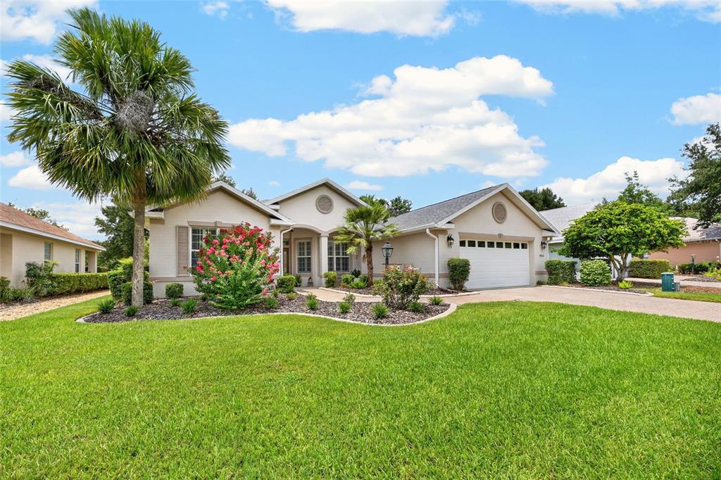 A single-story suburban house with a beige stucco exterior, a two-car garage, and landscaping — 8806 SW 83RD CIRCLE, OCALA, FL