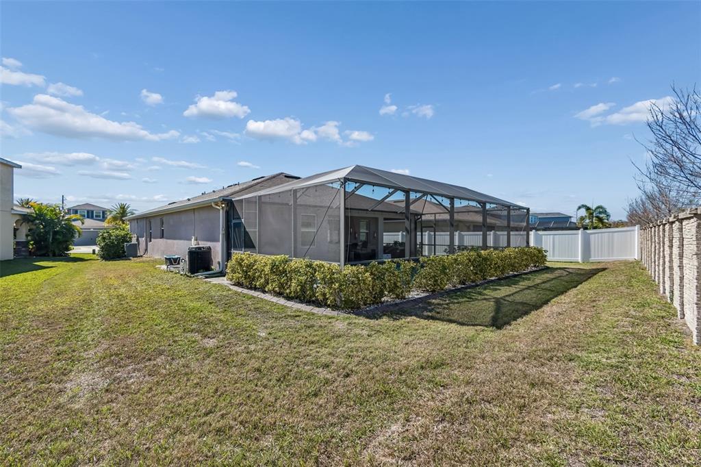 A backyard view of a house with a screened-in pool enclosure and landscaping — 7432 47TH AVENUE CIRCLE E, BRADENTON, FL