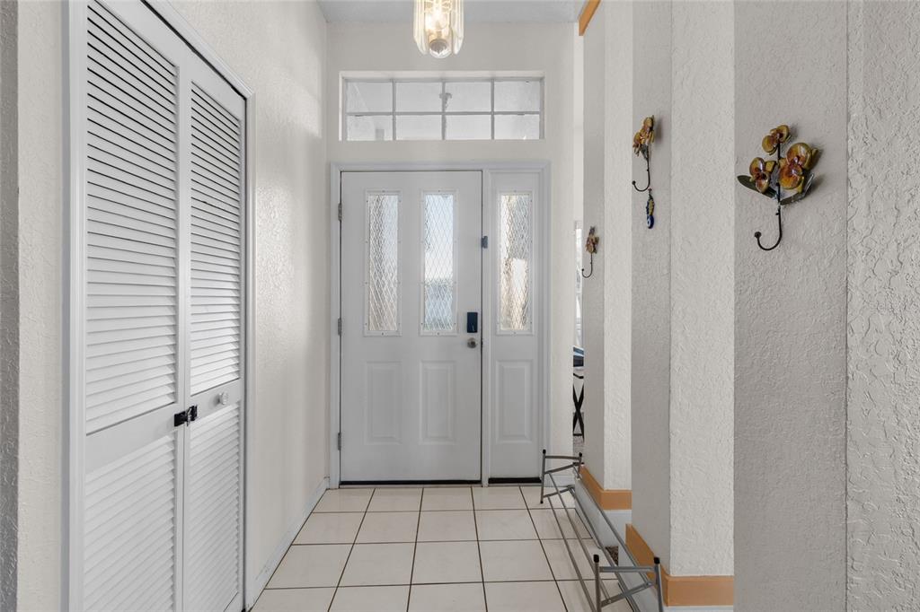 An entryway features white tiled floors, a louvered closet door, and a white front door — 10431 36TH STREET N, CLEARWATER, FL