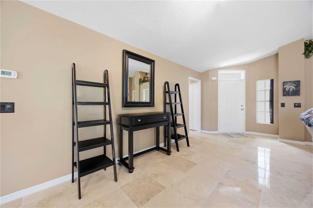 An entryway features a console table, mirror, two ladder shelves, and light-colored tile flooring — 1082 TEQUESTA TRAIL, LAKE WALES, FL