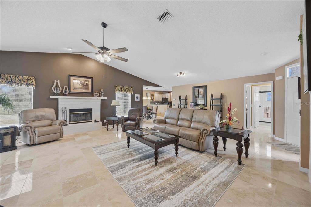 A living room features a fireplace, tile flooring, a ceiling fan, and neutral wall colors — 1082 TEQUESTA TRAIL, LAKE WALES, FL