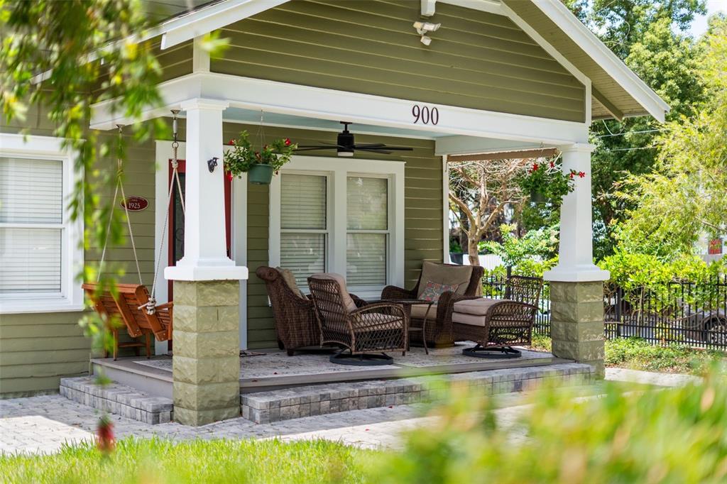 A green house with a covered front porch featuring wicker furniture and a hanging swing — 900 E PINE STREET, ORLANDO, FL