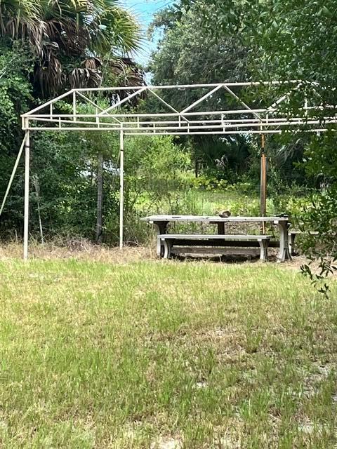 A metal canopy frame stands over a wooden picnic table in a grassy outdoor area — 20641 NW 302nd Street, Okeechobee FL 34972, OKEECHOBEE, FL