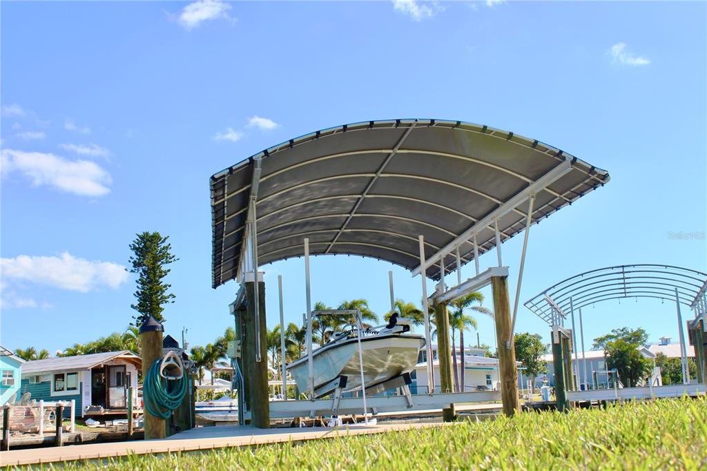 A boat on a lift under a curved canopy sits beside a wooden dock — 2744 SANDERLING COURT, ST JAMES CITY, FL