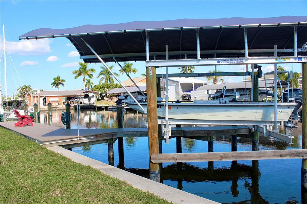 A boat sits in a covered lift at a residential dock along a canal — 2744 SANDERLING COURT, ST JAMES CITY, FL