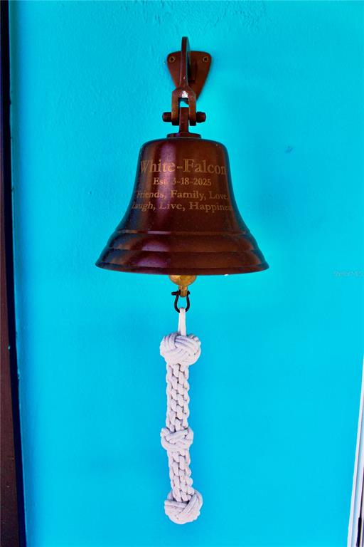 A decorative bronze bell with a rope pull is mounted on a bright blue wall — 2744 SANDERLING COURT, ST JAMES CITY, FL