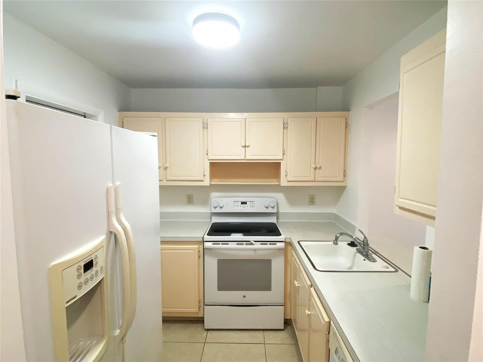 A galley kitchen features white appliances, light-colored cabinets, and a single-basin sink — 500 SE 2nd Avenue # 22, Deerfield Beach FL 33441, DEERFIELD BEACH, FL