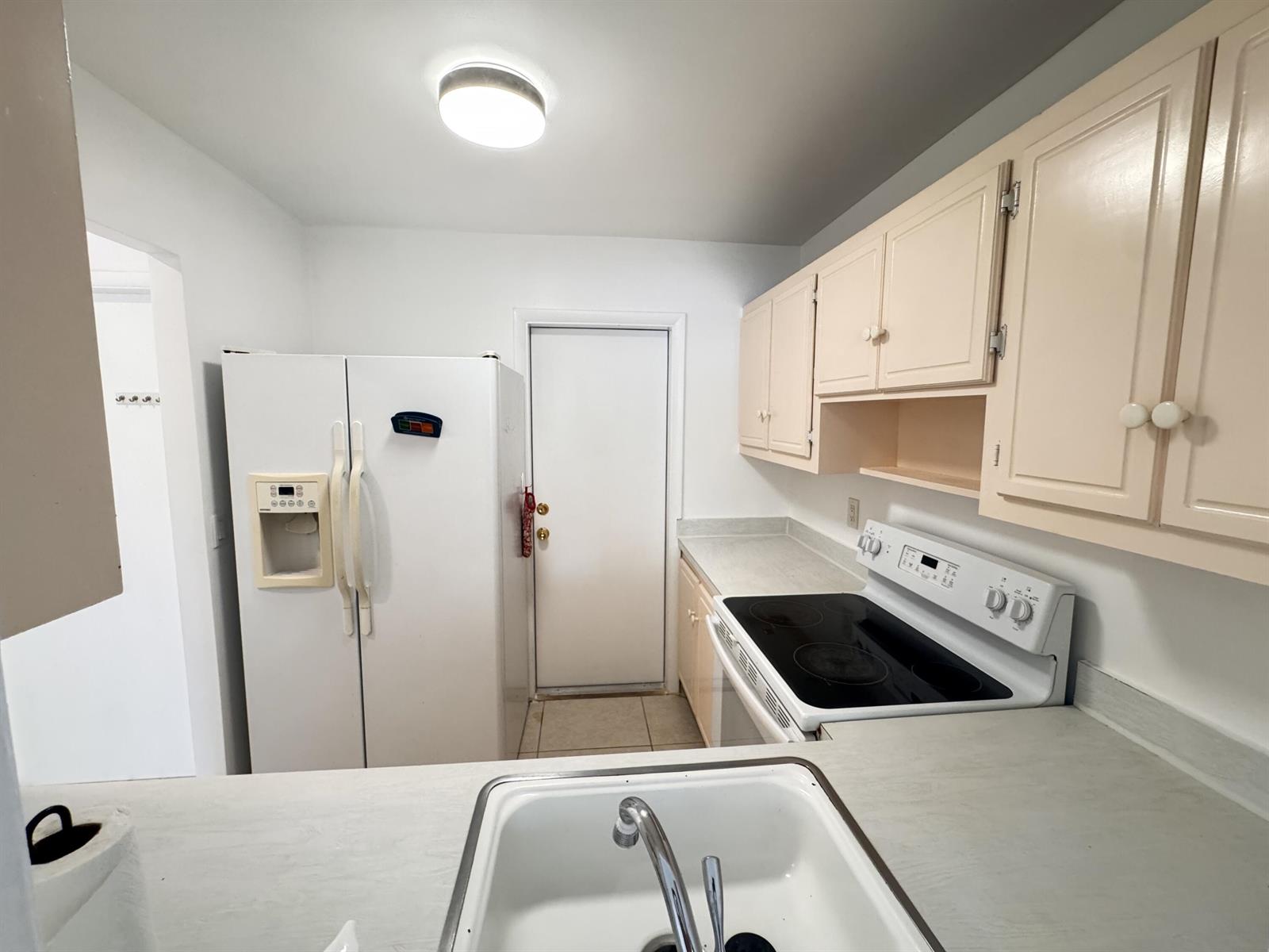 A kitchen features white appliances, light-colored cabinets, a sink, and a door to the outside — 500 SE 2nd Avenue # 22, Deerfield Beach FL 33441, DEERFIELD BEACH, FL