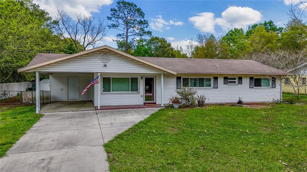 A single-story white house with a carport, a concrete driveway, and a grassy front yard — 831 NE 41ST AVENUE, OCALA, FL