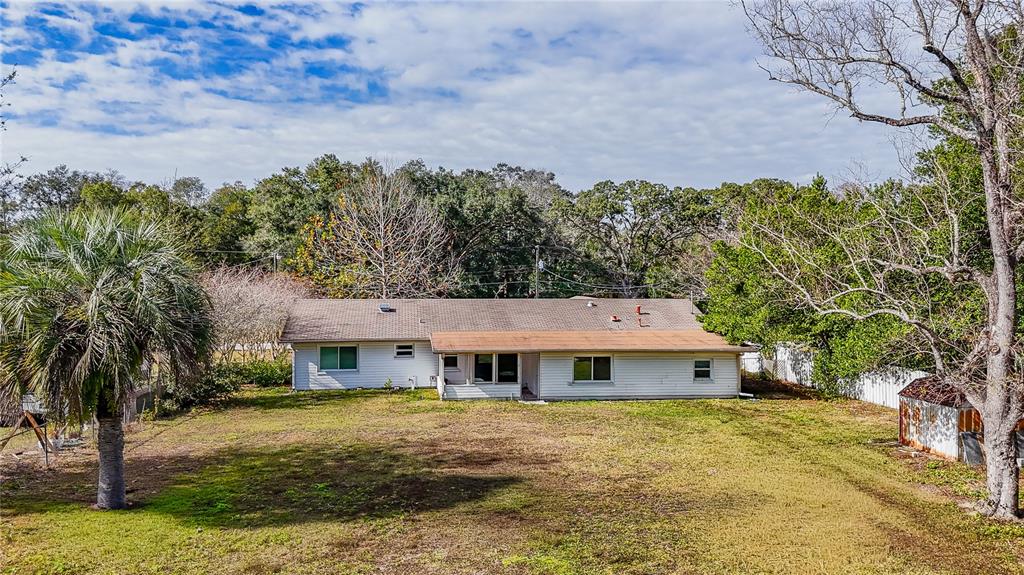 A single-story house with white siding and a brown roof sits on a grassy lot — 831 NE 41ST AVENUE, OCALA, FL