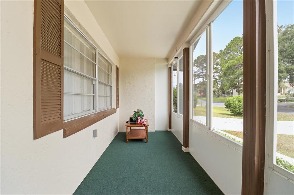A screened-in porch with green carpeting, brown shutters, and large windows overlooking a yard — 42 TRUMAN BOULEVARD, BEVERLY HILLS, FL