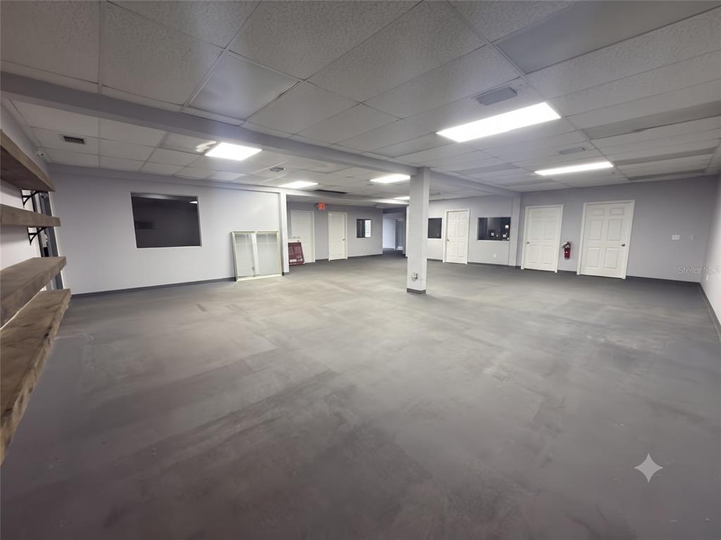 An open-plan commercial space features gray flooring, white walls, and a drop ceiling with lights — 1185 GOODEN CROSSING UNIT A, LARGO, FL