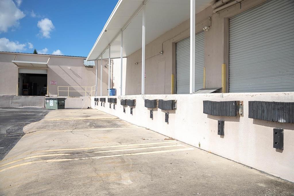 An exterior view of a commercial building featuring multiple loading dock bays with rubber bumpers — 1185 GOODEN CROSSING UNIT A, LARGO, FL