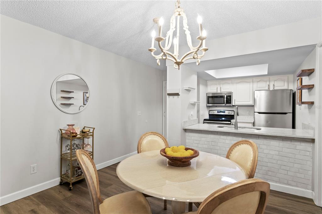 A dining area with a round table and chandelier opens to a kitchen with stainless appliances — 4506 S OAK DRIVE UNIT S92, TAMPA, FL