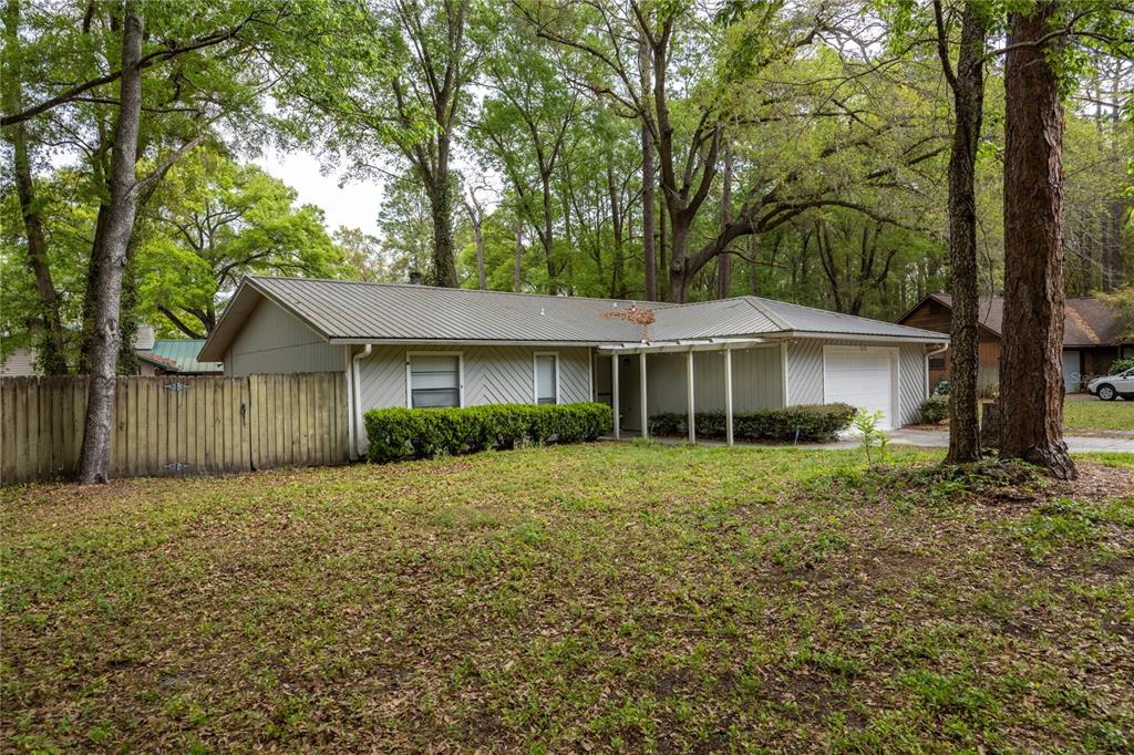 A single-story house with a metal roof, light-colored siding, and an attached garage — 7212 SW 18TH PLACE, GAINESVILLE, FL