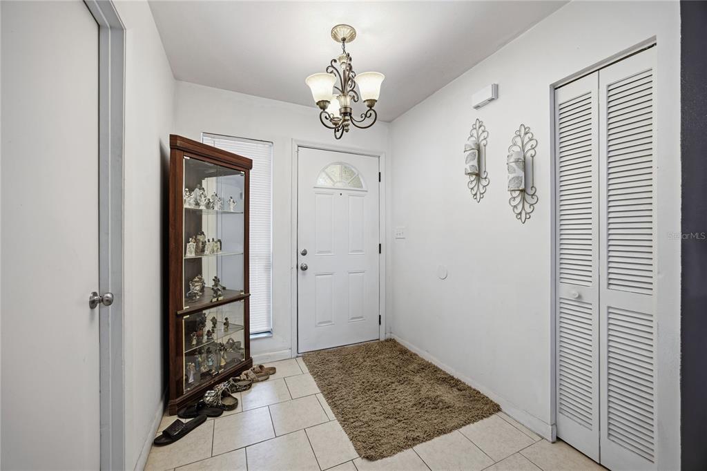An entryway features a white front door, a glass display cabinet, and a chandelier — 7212 SW 18TH PLACE, GAINESVILLE, FL