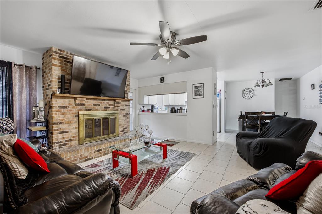 A living room features a brick fireplace, a ceiling fan, and tile flooring — 7212 SW 18TH PLACE, GAINESVILLE, FL