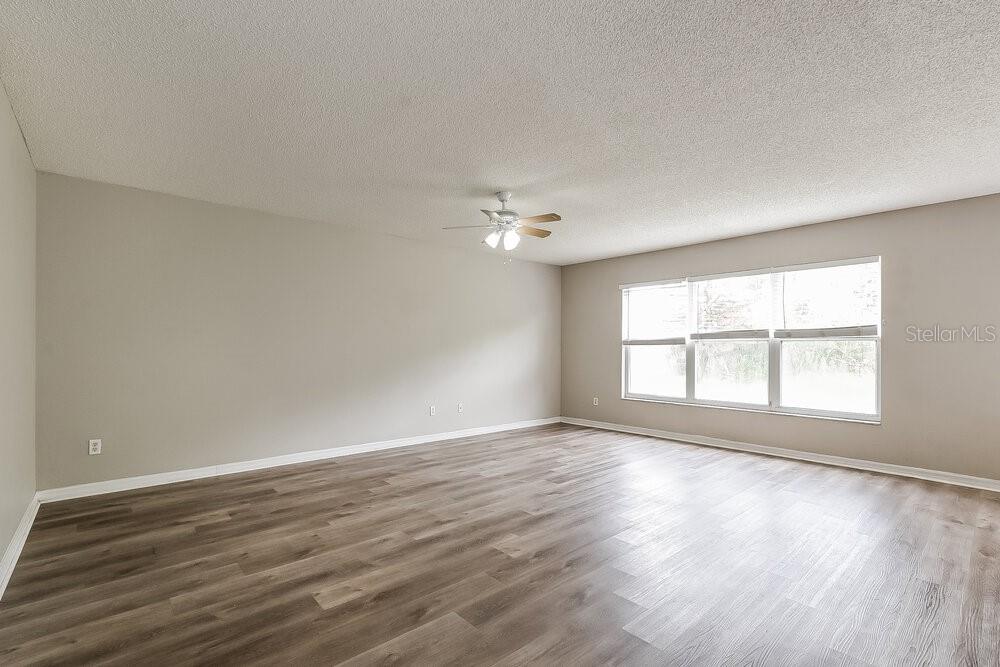 An empty room features light gray walls, wood-look flooring, and a ceiling fan — 14332 ABINGTON HEIGHTS DRIVE, ORLANDO, FL