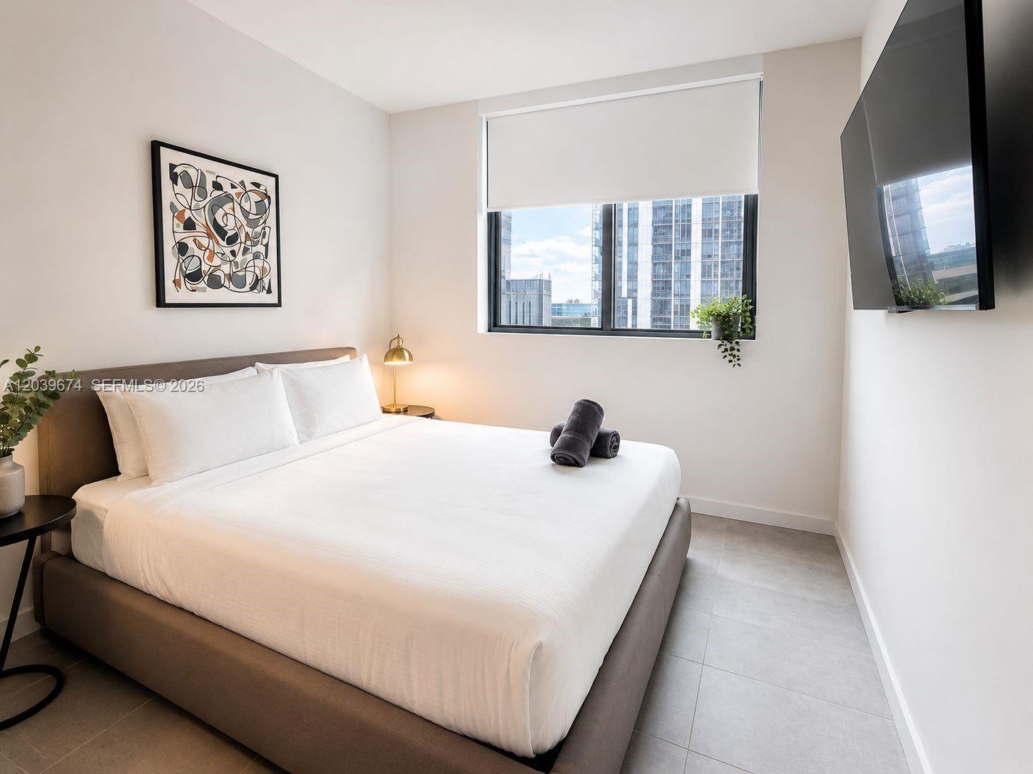A modern bedroom features a queen bed, a wall-mounted television, and a large window — 121 NE 5th St # 2408, Miami FL 33132, MIAMI, FL