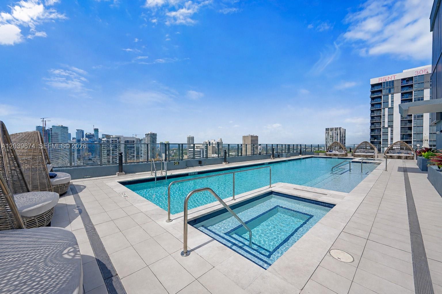 A rooftop swimming pool and hot tub overlook a city skyline under a blue sky — 121 NE 5th St # 2408, Miami FL 33132, MIAMI, FL