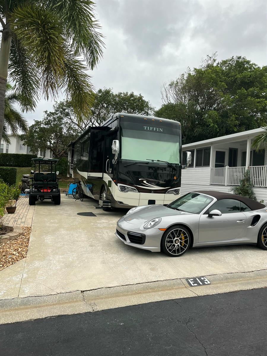 A Tiffin motorhome, a silver Porsche convertible, and a golf cart parked on a concrete driveway — 900 Juno Ocean Walk, Juno Beach FL 33408, JUNO BEACH, FL