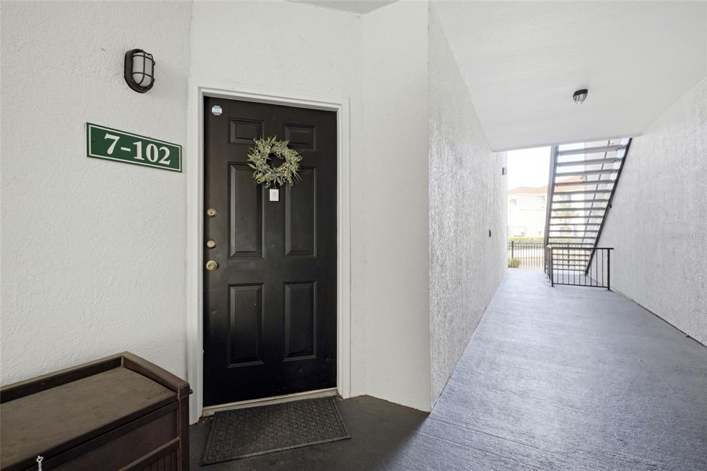 A black front door with a wreath is located in an outdoor apartment hallway — 2639 MAITLAND CROSSING WAY UNIT 102, ORLANDO, FL
