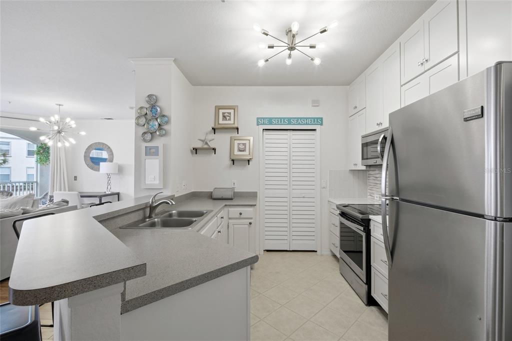 A kitchen features white cabinetry, stainless steel appliances, and a gray countertop breakfast bar — 2639 MAITLAND CROSSING WAY UNIT 102, ORLANDO, FL