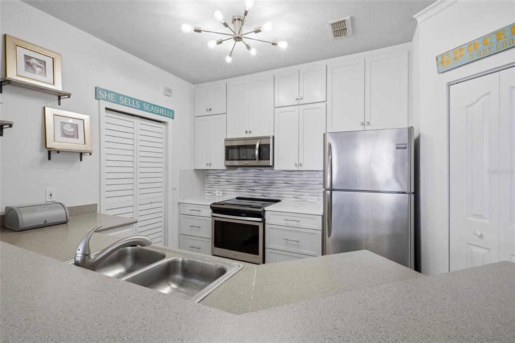 A kitchen features white cabinets, stainless steel appliances, a gray countertop, and a double sink — 2639 MAITLAND CROSSING WAY UNIT 102, ORLANDO, FL