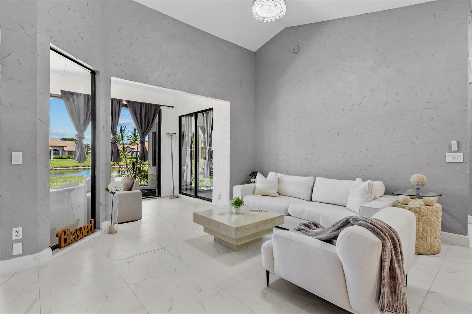 A living room with gray textured walls, white tile floors, and a view of a lake — 8180 Bellwort Place, Boynton Beach FL 33472, BOYNTON BEACH, FL