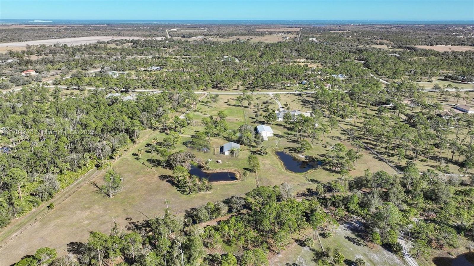 An aerial view shows a rural property with two ponds, several buildings, and wooded acreage — 27049 Seeger Dr, Punta Gorda FL 33955, PUNTA GORDA, FL