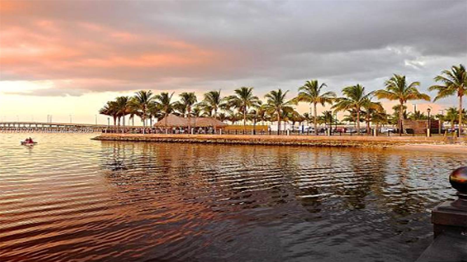 A row of palm trees lines a sandy beach along a calm body of water — 27049 Seeger Dr, Punta Gorda FL 33955, PUNTA GORDA, FL