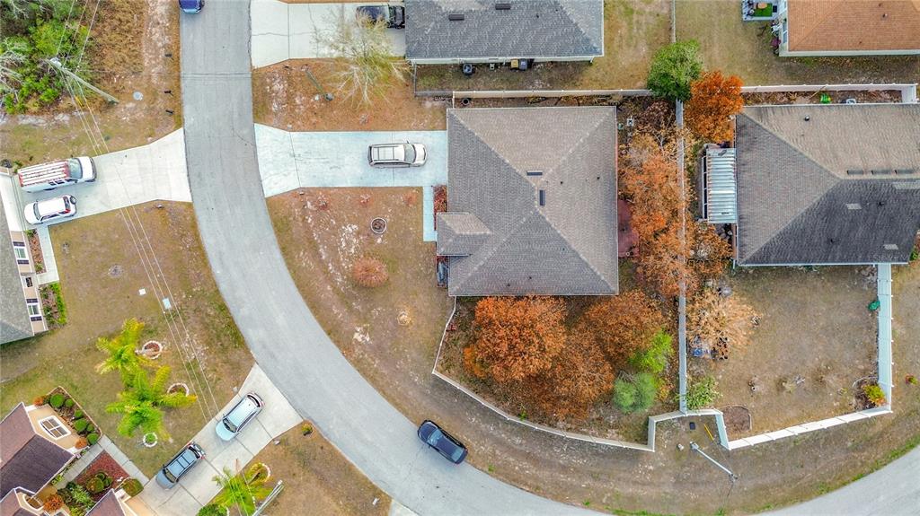An aerial view shows a suburban house with a fenced backyard and nearby parked cars — 1910 DOLPHIN DRIVE, KISSIMMEE, FL
