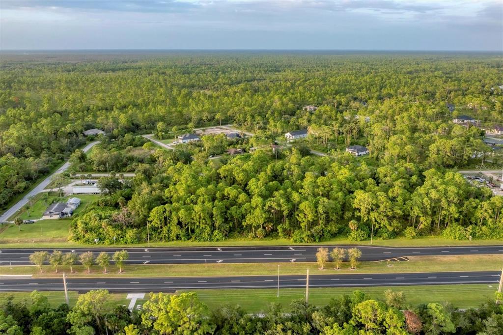 An aerial view shows a wooded lot situated next to a multi-lane divided highway — 11201 TAMIAMI TRAIL S, NORTH PORT, FL