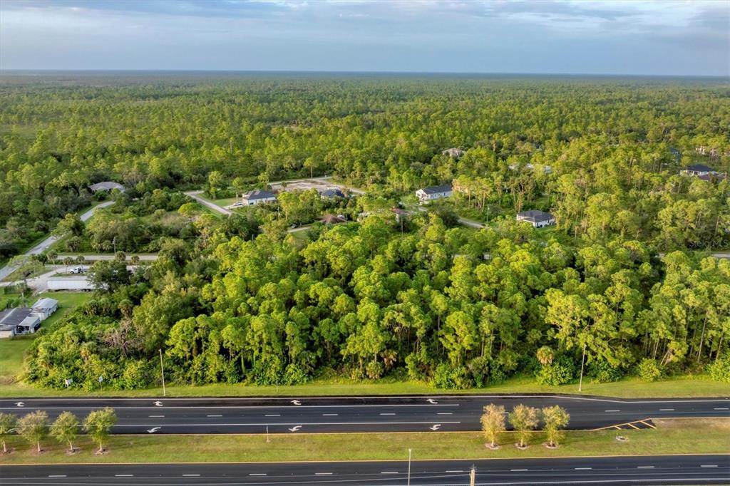 An aerial view shows a wooded lot situated next to a multi-lane highway — 11201 TAMIAMI TRAIL S, NORTH PORT, FL