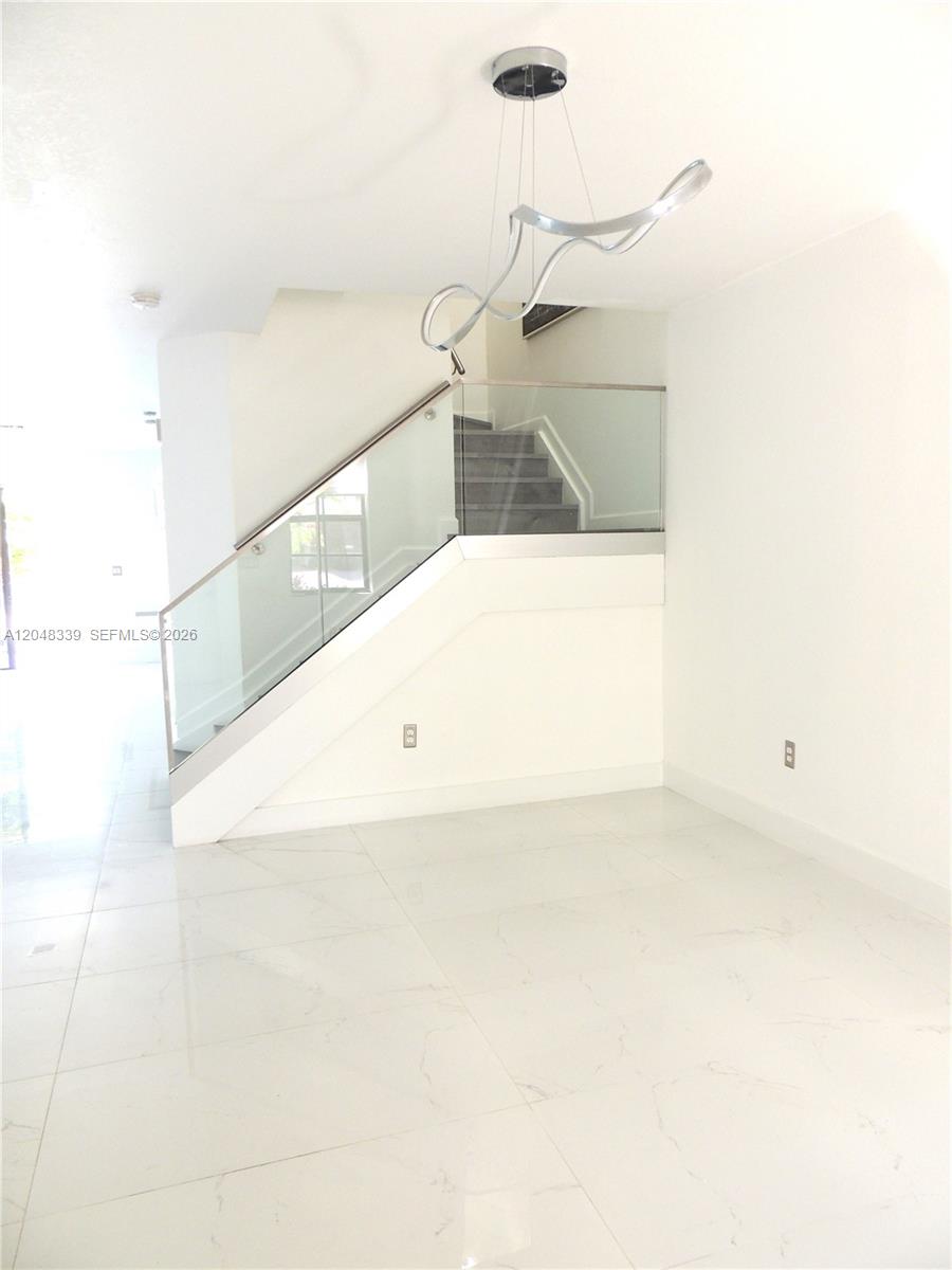 A bright room features white tile floors, a glass-railed staircase, and a modern sculptural chandelier — 9336 W 34th Ct, Hialeah FL 33018, HIALEAH, FL
