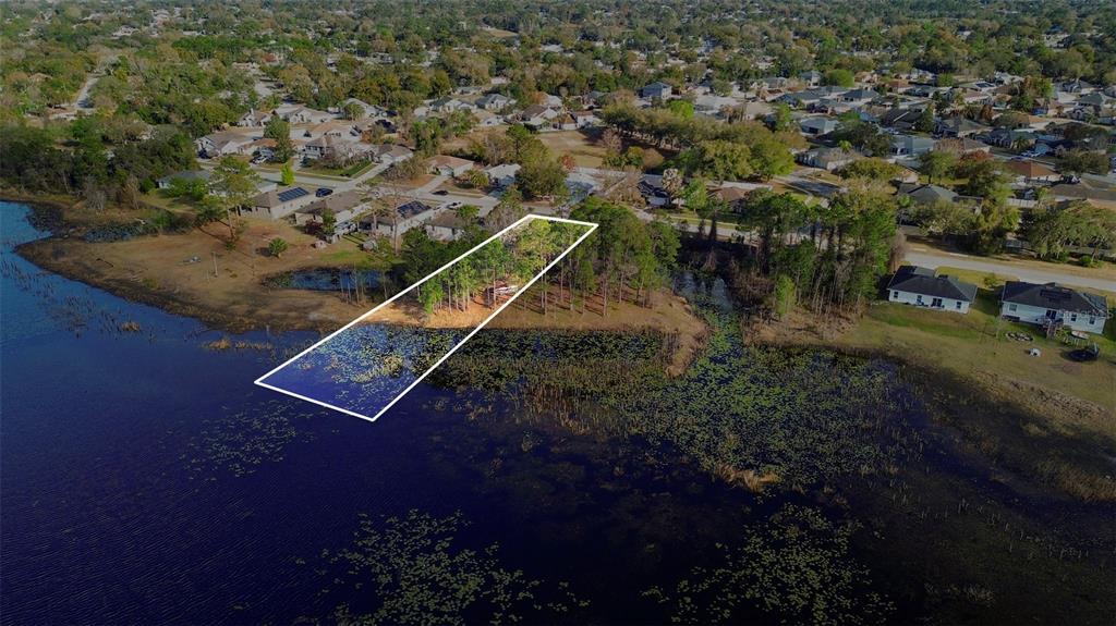 An aerial view shows a rectangular plot of land extending into a lake — 466 HAVERSHAM ROAD, DELTONA, FL