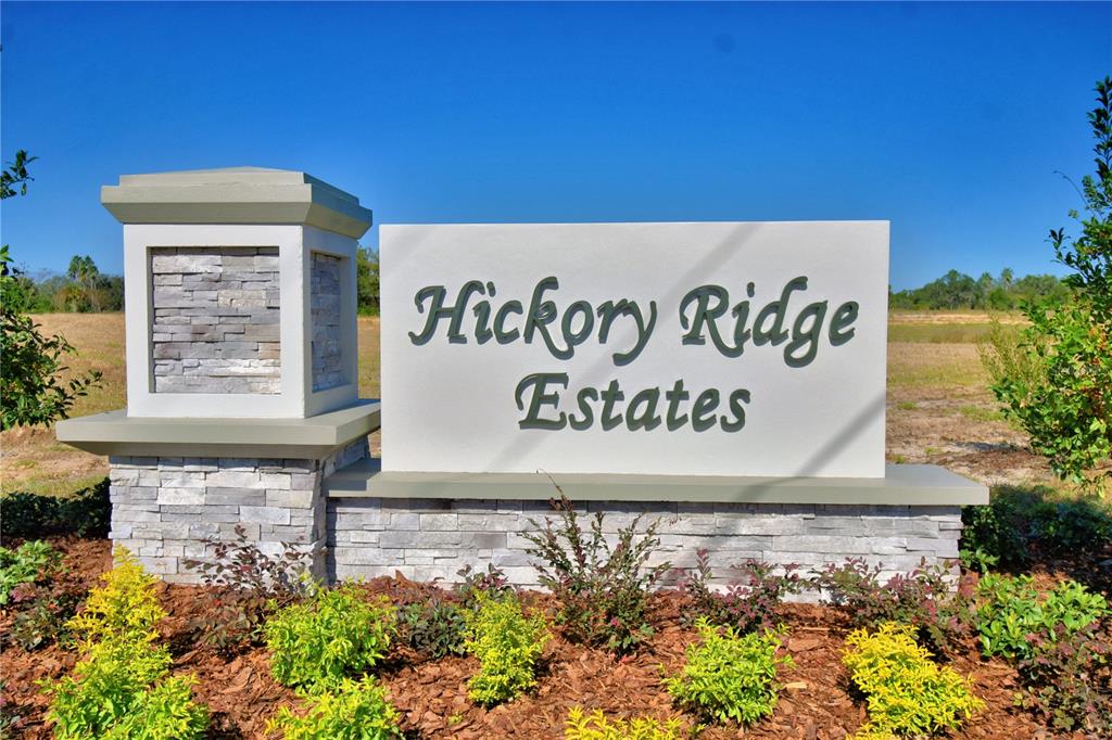 A stone and concrete monument sign for Hickory Ridge Estates stands in a landscaped area — 1211 HICKORY NUT DRIVE, LAKE WALES, FL