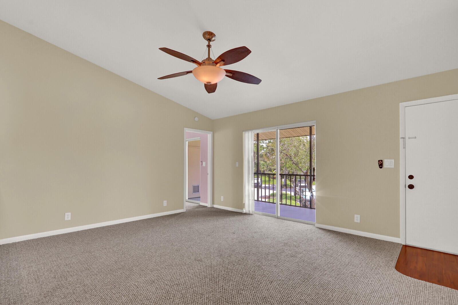 An empty carpeted room features a ceiling fan, a sliding glass door, and a balcony — 6563 Chasewood Drive # F, Jupiter FL 33458, JUPITER, FL