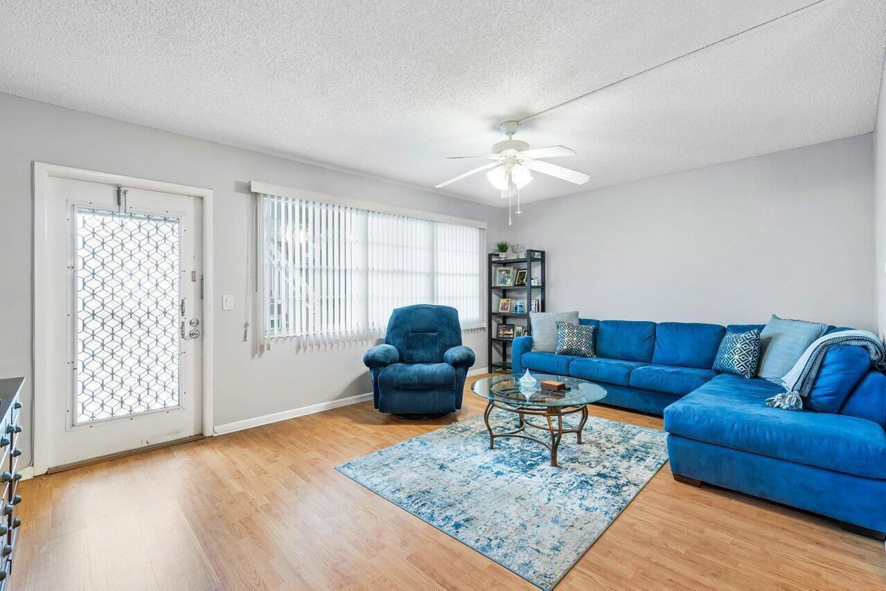 A living room features a blue sectional sofa, a matching recliner, and a glass coffee table — 2046 Rexford C, Boca Raton FL 33434, BOCA RATON, FL
