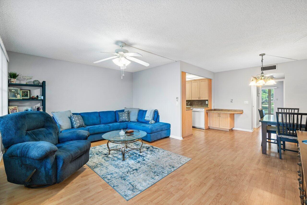 A living room with a blue sectional, a matching recliner, and an adjacent dining area — 2046 Rexford C, Boca Raton FL 33434, BOCA RATON, FL